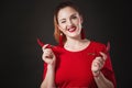 A chic red-haired young woman in a red overalls holds a hot chili pepper in her hands Royalty Free Stock Photo