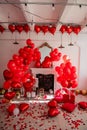 Chic room decoration for Valentines Day. Fireplace near white wall decorated with red heart Royalty Free Stock Photo