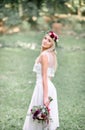 Chic young bride in red wreathe poses in the garden