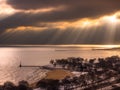 Chicago, IL - November 28th 2018: Dramatic yellow sun rays shine through a crack in cumulus clouds over Lake Michigan water and Royalty Free Stock Photo