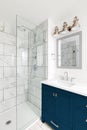 A blue vanity in a modern bathroom with a tiled shower.