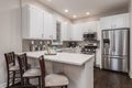 A white kitchen with bar stools at the counter top.