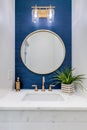 A white and blue half bathroom with gold accents.