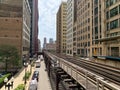 View of el train as it approaches on elevated track above Wabash Ave, casting shadows onto street Royalty Free Stock Photo