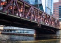 View of Lake St bridge crossing Chicago River, where commuters rush through shadows from morning light and bridge structures