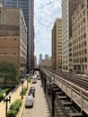 View of Chicago Loop on Wabash Ave, where el tracks cast patterns onto street below, and clouds cover the sky while train Royalty Free Stock Photo