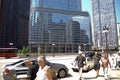 Pedestrians on the sidewalk along Wacker Drive with mirrored buildings in the background