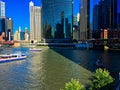 Chicago River during a colorful summer, with tour boats covering the water while tourist and commuter alike utilize the riverwalk