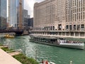 Chicago River congestion with very large Odyssey tour boat filled with tourists, followed by a water taxi, and observed by people