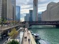 Chicago River recreation with paddleboats and retro motorboats moored at river`s edge, pedestrians walking with their shadows, an