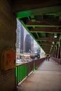 Chicago River`s dyed green color reflects onto DuSable bridge as pedestrians cross looking at phones Royalty Free Stock Photo