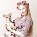 Chick & puppy: beautiful blond pinup girl with red lips & curlers in her hair holding a small cute dog happy smiling Royalty Free Stock Photo