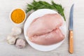 Chicken breast fillet, garlic, spices, dill and knife on wooden Royalty Free Stock Photo