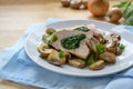 Chicken breast fillet stuffed with spinach, served with mushrooms and parsley garnish on a blue napkin and a light wooden table, Royalty Free Stock Photo