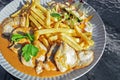 Chicken breast fillets with sauce, french fries and salad on a plate in an outdoor restaurant on a sunny summer day, selected Royalty Free Stock Photo