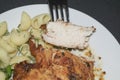 Chicken breast fried with spices, boiled pasta with herbs, a metal fork with a cut piece of breast on a white plate Royalty Free Stock Photo