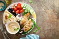 Chicken breast grilled with fresh vegetables, olives, feta cheese, flatbread and hummus, top view Royalty Free Stock Photo