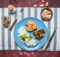 Chicken breast with mushroom sauce and rice on a blue plate with a knife and fork wooden rustic background top view Royalty Free Stock Photo