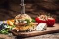 Chicken burger with blue cheese and arugula in a sesame bun on a rustic wood Royalty Free Stock Photo