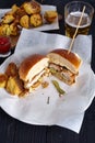 Chicken burger cuted in two halfs with potatoes and beer
