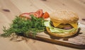 Chicken Burger with Fresh Tomatoes and Dills, set on Wooden Board