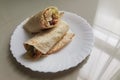 Chicken burrito warp serve on white plate against window light