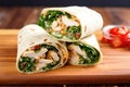chicken caesar wrap neatly sliced and displayed on a warm wooden board