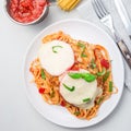 Chicken caprese with tomato and mozzarella cheese, served with linguine, tomato pasta sauce and basil, square, top view Royalty Free Stock Photo