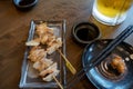 Chicken cartilage grilled on a wooden skewer, placed on a dark plate on a wooden table with sauce Royalty Free Stock Photo