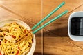 Chicken chow mein and chopsticks on wooden table Royalty Free Stock Photo