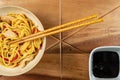 Chicken chow mein and chopsticks on wooden table Royalty Free Stock Photo