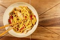 Chicken chow mein and chopsticks on wooden table Royalty Free Stock Photo