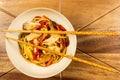 Chicken chow mein and chopsticks on wooden table Royalty Free Stock Photo