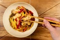 Chicken chow mein and chopsticks on wooden table Royalty Free Stock Photo