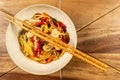 Chicken chow mein and chopsticks on wooden table Royalty Free Stock Photo