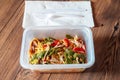 Chicken chow mein noodles in a plastic take away box or container on a wooden table. Quick and tasty Asian style meal for Royalty Free Stock Photo