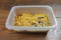 Chicken chow mein ready meal in a plastic container on a wooden table. Chinese style tasty noodles with sauce and vegetables. Royalty Free Stock Photo