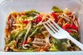 Chicken chow mein noodles in a plastic take away box or container on a wooden table. Quick and tasty Asian style meal for