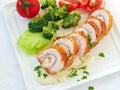 Chicken cordon bleu sliced with creamy white sauce and vegetables, top view