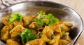 Chicken curry in a balti dish on wooden table.