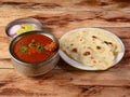 Chicken Curry / Masala, with prominent Leg Piece with Tava Roti, Indian FlatBread, served over a rustic wooden table, selective