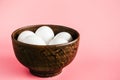 Chicken egg in a clay bowl on a pink background