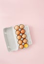 Chicken egg half broken among eggs carton pink background top vi