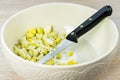 Chicken egg hard boiled sliced in white salad bowl on wooden table background, knife Royalty Free Stock Photo