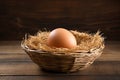 Chicken egg in a wicker nest basket on a wooden table. Royalty Free Stock Photo