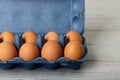 Chicken eggs in a blue package on a gray wooden background. Royalty Free Stock Photo