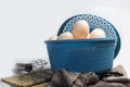 Chicken eggs in a blue plastic basket with a clean white back next to the basket The egg beater is ready for cook eggs Royalty Free Stock Photo