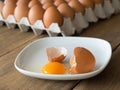 Chicken eggs cracked in white dish. The dish is placed on a wooden table. Royalty Free Stock Photo