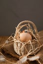 Chicken eggs of different brown and beige shades in wicker basket of vines on a wooden table. Easter background Royalty Free Stock Photo