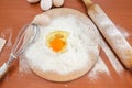 Chicken eggs, flour, whisk and rocking chair on the table. The process of making dough. Broken egg in flour on a wooden board. Vie Royalty Free Stock Photo